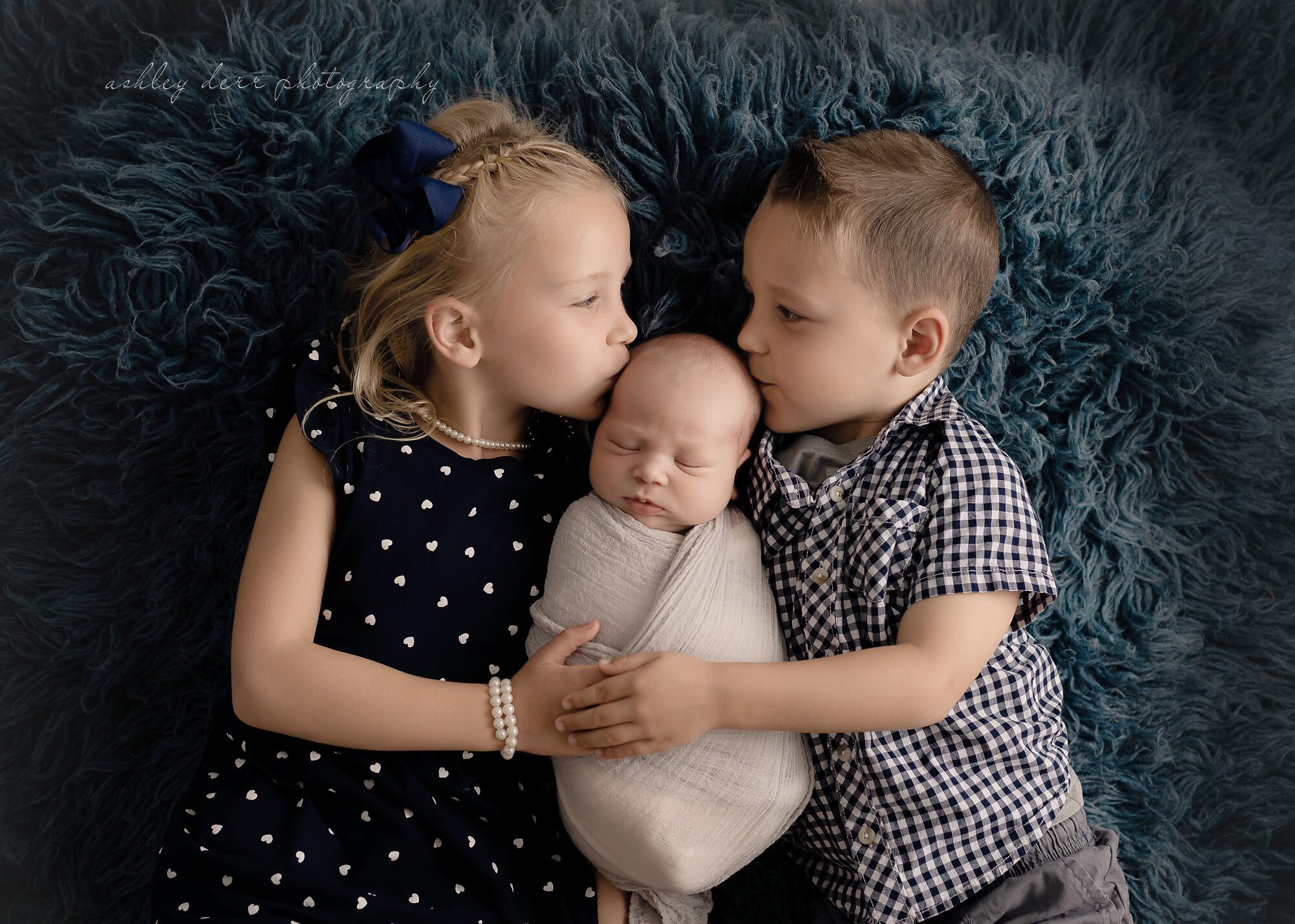 Siblings kissing newborn baby brother during photography session in pittsburgh pa